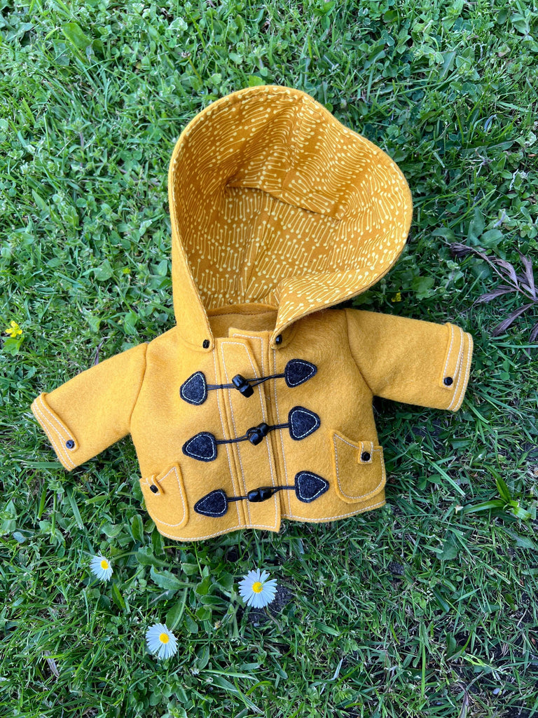 Why Wool Felt Is the Best for Toymaking - yellow felt doll jacket on grass with flowers.