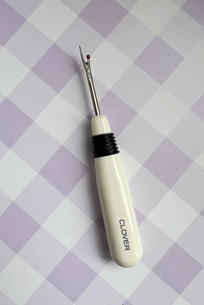 Clover needle threader on a checkered background