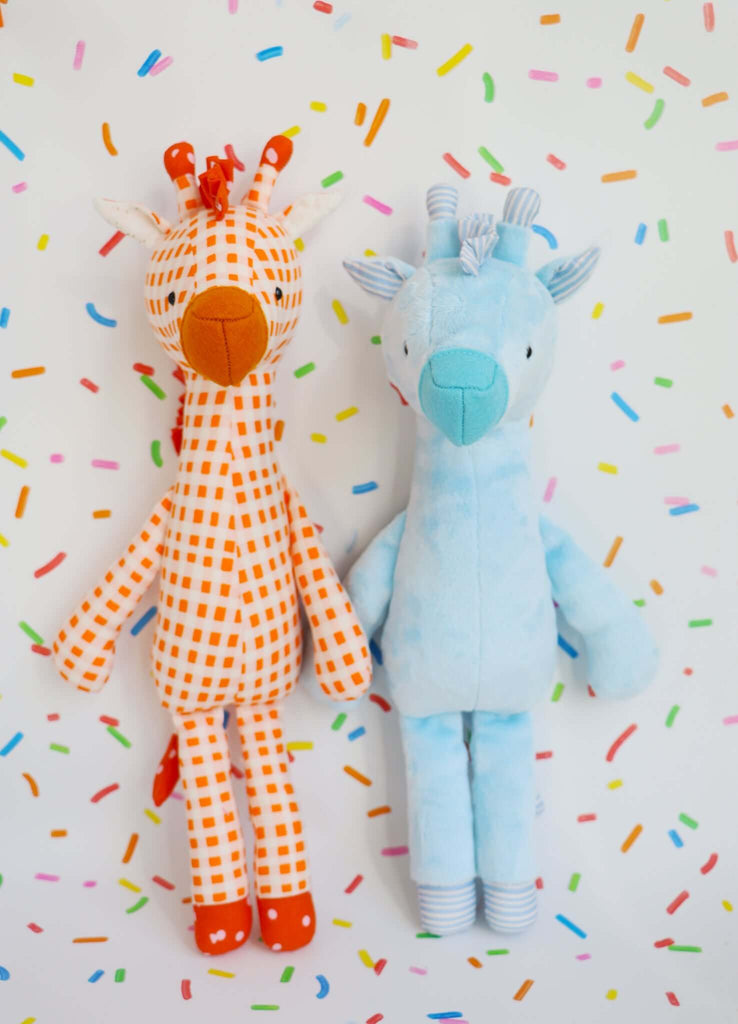 Two stuffed giraffes, one cotton and the other minky, on a background with colorful sprinkles.