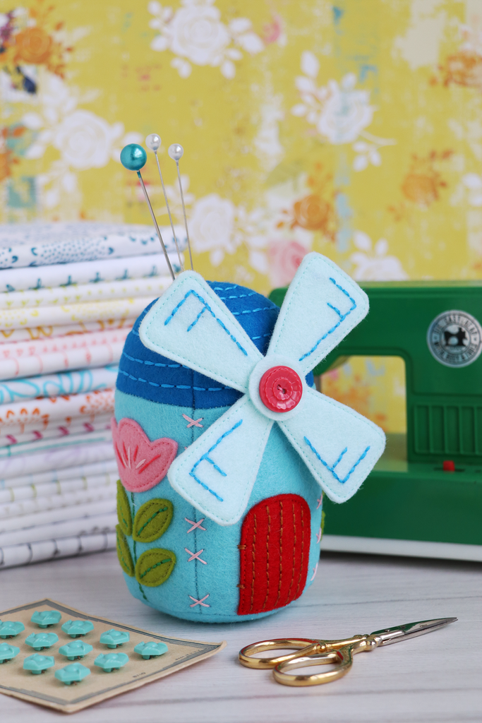  windmill-shaped felt pin cushion with sewing tools on a floral background