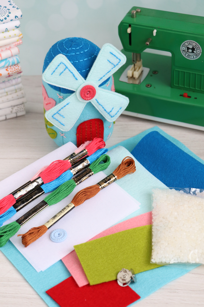 Contents of the windmill pincushion sewing kit including embroidery floss, felt sheets, and poly beads