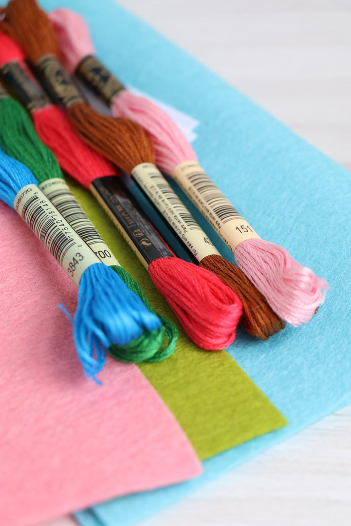 Set of embroidery floss with colorful ends on a blue and pink fabric background