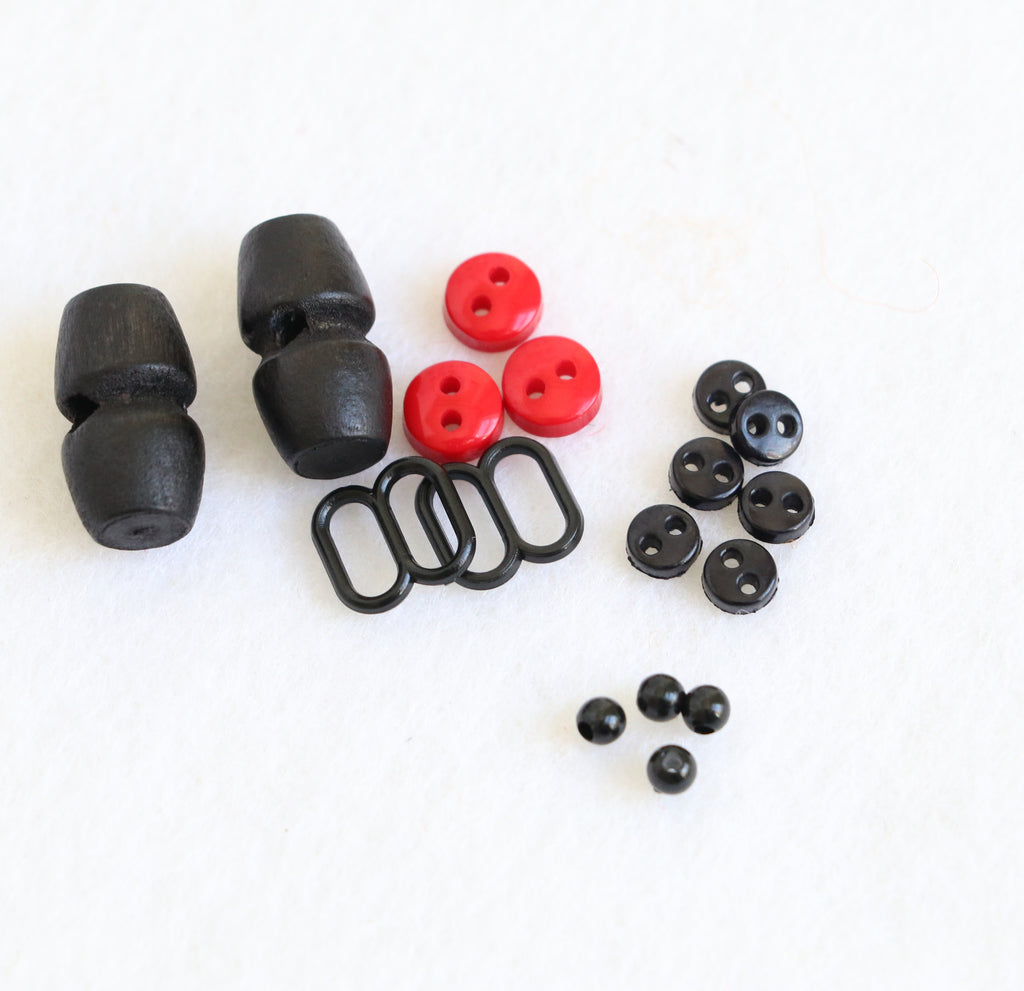 Daryl & Russ sewing kit components including wooden beads, buttons, and rings for creating felt dogs.