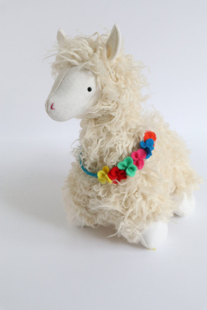 Curly plush llama soft toy with colorful felt flower garland necklace, made using a DIY sewing pattern from RicRac.